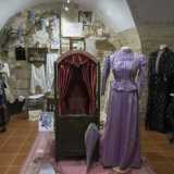 Ecco poi spiccare un elegante vestito lungo da donna color viola. Presenta una vita sottilissima, delle maniche gonfie "a prosciutto" e una gonna a forma di campana che si allunga lambendo il pavimento